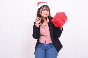 bellissimo asiatico ragazza nel completo da uomo allegro Sorridi con Santa Claus cappello in posa con Natale regalo scatola i regali e sollevamento scatola puntamento su su bianca sfondo per promozione, pubblicità, striscione, tabellone foto