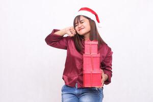 bellissimo giovane sud-est asiatico ragazza con un' Sorridi trasporto 3 scatole di i regali a Natale indossare un' Santa Claus cappello indossare un' moderno rosso camicia su un' bianca sfondo per promozione e pubblicità foto