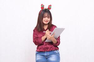 bellissimo giovane sud-est asiatico donna sorridente scrittura ordine mentre trasporto il computer portatile tavoletta a Natale Santa Claus fascia per capelli indossare rosso camicia moderno bianca sfondo per promozione e pubblicità foto