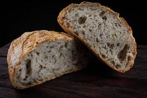 un' pagnotta di pane tagliare nel metà su un' di legno tavola. arte pane. foto