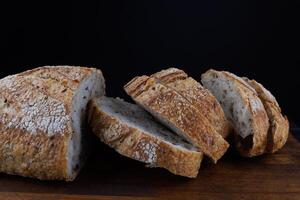 tagliare pagnotta con semi su un' di legno tavola. affettato pezzi di pane. arte pane. foto