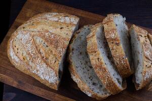 tagliare pagnotta con semi su un' di legno tavola. affettato pezzi di pane. arte pane. foto