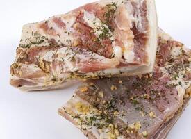 appetitoso salato lardo con strati di carne con aglio e erbe aromatiche. Due pezzi di salato lardo su un' bianca sfondo. foto