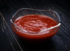 ketchup nel un' bicchiere tazza su un' nero sfondo. foto