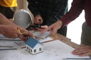 costruzione e struttura concetto di ingegnere o architetto incontro per progetto Lavorando con compagno e ingegneria utensili su modello edificio e planimetria nel Lavorando luogo, contrarre per tutti e due aziende. foto