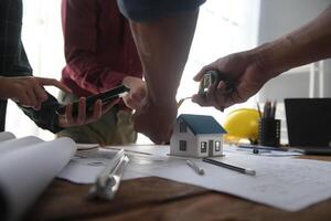 costruzione e struttura concetto di ingegnere o architetto incontro per progetto Lavorando con compagno e ingegneria utensili su modello edificio e planimetria nel Lavorando luogo, contrarre per tutti e due aziende. foto