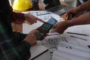 costruzione e struttura concetto di ingegnere o architetto incontro per progetto Lavorando con compagno e ingegneria utensili su modello edificio e planimetria nel Lavorando luogo, contrarre per tutti e due aziende. foto