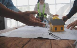 costruzione e struttura concetto di ingegnere o architetto incontro per progetto Lavorando con compagno e ingegneria utensili su modello edificio e planimetria nel Lavorando luogo, contrarre per tutti e due aziende. foto