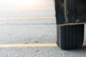 vicino di Usato auto pneumatici su asfalto strada con sole leggero nel il mattina volta. con giallo linea attraverso il pavimento. foto