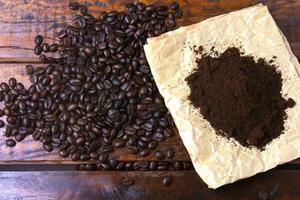 chicchi di caffè tostati e caffè macinato su carta su tavola rustica foto