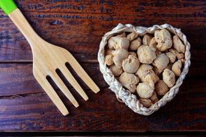 carne di soia, pezzi in un cesto a forma di cuore. pezzi di semi di soia crudi su fondo di legno rustico foto