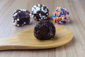 brigadeiro, brigadier, dolce al cioccolato tipico della cucina brasiliana ricoperto di particelle, su fondo in legno. foto