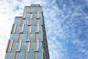 bicchiere edificio con trasparente facciata di il edificio e blu cielo. strutturale bicchiere parete riflettendo blu cielo. astratto moderno architettura frammento. contemporaneo architettonico sfondo. foto