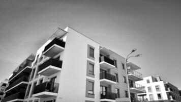frammento di il di edificio facciata con finestre e balconi. moderno appartamento edifici su un' soleggiato giorno. facciata di un' moderno Residenziale costruzione. nero e bianca. foto