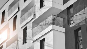 frammento di un' facciata di un' edificio con finestre e balconi. moderno appartamento edifici su un' soleggiato giorno. facciata di un' moderno appartamento costruzione. nero e bianca. foto