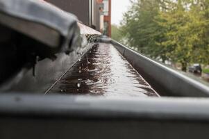 pioggia flussi giù il tetto in il drain tubo foto
