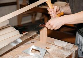 mani taglio legna con sega su un' polveroso laboratorio tavolo foto