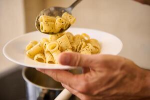 avvicinamento scrosciante italiano pasta su bianca piatto prima placcatura su e servendo per il i clienti foto