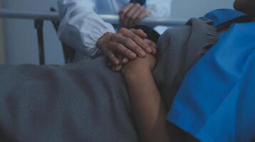 ritagliata tiro di un' femmina infermiera hold sua anziano del paziente mano. dando sostegno. medico porzione vecchio paziente con Alzheimer patologia. femmina badante Tenere mani di anziano uomo foto