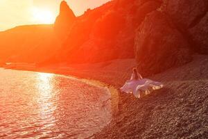 misterioso donna silhouette lungo capelli passeggiate su il spiaggia oceano acqua, mare ninfa vento ascolta per il onda. lanci su un' lungo bianca vestire, un' divine tramonto. artistico foto a partire dal il indietro senza un' viso