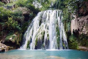 maestoso cascata a cascata giù coperto di muschio rocce in rinfrescante piscina sotto foto