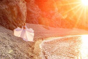 misterioso donna silhouette lungo capelli passeggiate su il spiaggia oceano acqua, mare ninfa vento ascolta per il onda. lanci su un' lungo bianca vestire, un' divine tramonto. artistico foto a partire dal il indietro senza un' viso