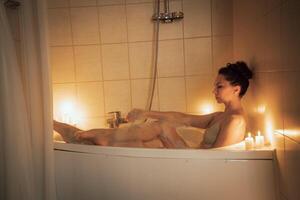 un' donna è seduta nel un' vasca da bagno con candele illuminato in giro suo. scena è rilassante e calmante. foto