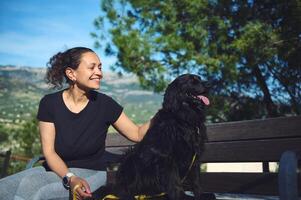 contento donna e sua cocker spaniel Dio guardare modo, seduta su il panchina contro montagne natura sfondo. donna a piedi animale domestico nel il natura foto