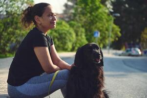 lato ritratto di un' bellissimo giovane adulto donna e sua nero cocker spaniel cane mentre a piedi esso su guinzaglio. giocando animali domestici. il concetto di amore, cura e empatia per domestico animali foto