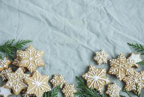 ramoscelli di abete rosso con biscotti di panpepato natalizio sullo sfondo di tessuto stropicciato di lino verde
