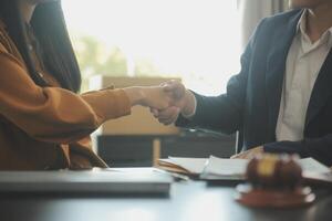 concetto di giustizia e diritto. il consulente legale presenta al cliente un contratto firmato con martelletto e diritto legale o una riunione del team legale presso uno studio legale in background foto