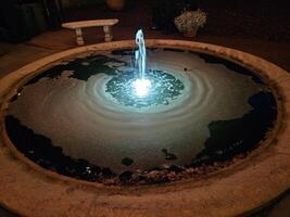 un' semplice acqua Fontana con luminosa luci a notte nel un' storico Casa e giardino foto