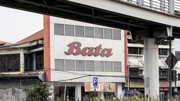il cartello e logo su il costruzione, il famoso marca di il catena di calzature I negozi, sotto il nome di bata. Giacarta, Indonesia, Maggio 7 2024 foto