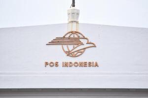 pos Indonesia logo e cartello tavola su superiore di edificio con indonesiano bandiera. Giacarta, Indonesia, Maggio 1, 2024 foto