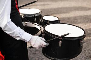 mani di un' persona Tenere bacchette giocando nel un' in marcia gruppo musicale. foto