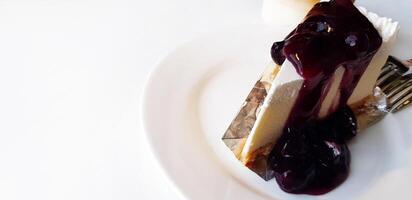 vicino su pezzo di mirtillo torta di formaggio nel bianca piatto con cucchiaio e su bianca tavolo con copia spazio a bar negozio. fatti in casa e dolce cibo, dolce e malsano vita stile concetto foto