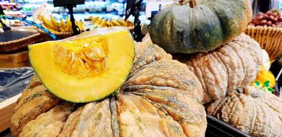 vicino su fresco fetta di zucca mettendo su altro zucca a supermercato con sfocato altro frutta sfondo. biologico o freschezza cibo concetto foto