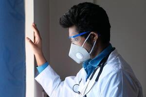 medico indossare viso protettivo maschera guardare attraverso finestra foto