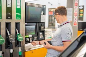 il uomo paga per carburante con un' credito carta su terminale di Fai da te Riempimento stazione nel Europa. alto qualità foto