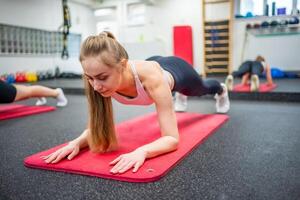 giovane sport donna fare esercizio nel un' tavola posizione per il addominali a palestra, lei esercizio per forte e bene sano. alto qualità foto