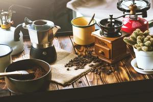 tazza di caffè, fagioli che girano e ingredienti per fare il caffè e accessori sul fondo di legno del tavolo. concetto di preparazione del caffè
