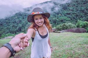 amante donne e uomini asiatici viaggiano rilassarsi durante le vacanze. tenersi per mano correndo sul prato. legno di natura selvaggia sulla montagna. foto