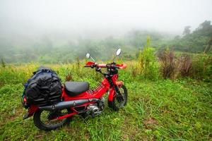 mototurismo parcheggiato su un prato di montagna sotto la pioggia e la nebbia in thailandia foto