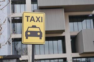 avvicinamento foto di un' giallo Taxi In piedi cartello allegato per un' metallo polo