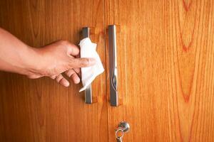 pulizia della maniglia della porta con un fazzoletto da vicino foto