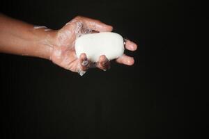 giovane che si lava le mani con acqua calda e sapone foto