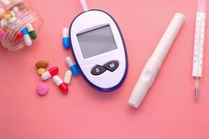 sangue zucchero misurazione kit, pillole e termometro su rosa foto