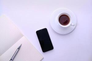 un' inteligente Telefono con un' tazza di caffè su il bianca sfondo. foto