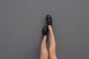 gambe di bella giovane donna in scarpe alla moda su sfondo grigio