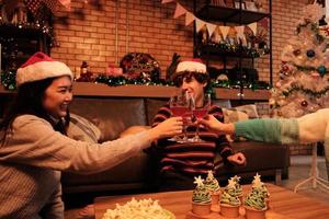 la famiglia e gli amici della felicità stanno festeggiando, alzando i bicchieri e sorridendo allegro con bevande, cupcakes e popcorn nel soggiorno di casa, decorato per la festa di Natale e il giorno di Capodanno. foto